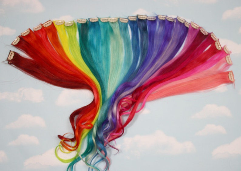 K&ouml;nnte beinhalten: Ein Set regenbogenfarbener Clip-in-Haarverl&auml;ngerungen. Die Extensions sind in einem Regenbogenmuster angeordnet, mit Rot, Orange, Gelb, Gr&uuml;n, Blau, Indigo und Violett.