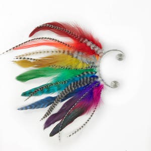 Könnte beinhalten: Regenbogenfeder-Ohrring mit einem silbernen Draht und einem Spiraldesign. Die Federn sind in einem Farbverlauf von Rot bis Lila angeordnet.