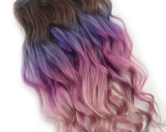May include: Two wefts of wavy hair extensions with a brown base and ombre color transitioning to purple, blue, and pink.