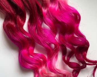 May include: Pink, red, and brown ombre hair extensions with a wavy texture.