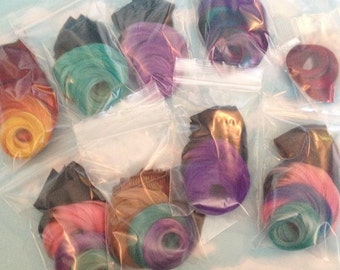 Puede incluir: Varias bolsas de plástico que contienen mechones de extensiones de cabello de colores. Los colores incluyen morado, verde azulado, rosa, marrón y amarillo.