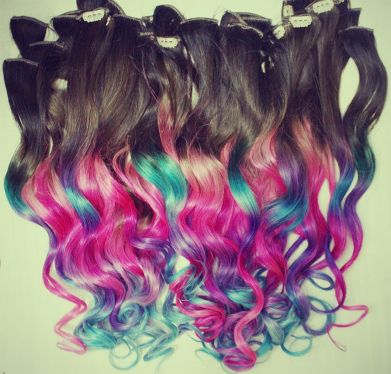 K&ouml;nnte beinhalten: Ein Set welliger Haarverl&auml;ngerungen mit einer dunkelbraunen Basis und einem Ombre-Farbverlauf von Pink &uuml;ber T&uuml;rkis zu Lila.