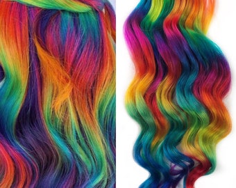 May include: Rainbow colored hair extensions with a wavy texture. The hair is a mix of bright colors, including red, orange, yellow, green, blue, and purple.