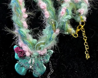 ハンドメイドのファイバーアートフローラルネックレス。パステルカラーのディテールが施された、職人が手がけたユニークなテキスタイルジュエリー。