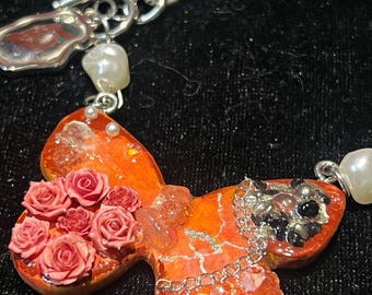 花のディテールが施された手作りの粘土製バタフライネックレス。ギフトに最適なユニークな職人のジュエリー。