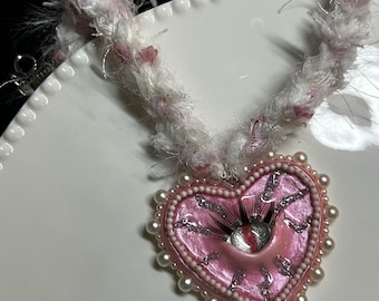 ふわふわのコードが付いた手作りの粘土製ハートアイネックレス。ギフトに最適な、気まぐれな職人のジュエリー。