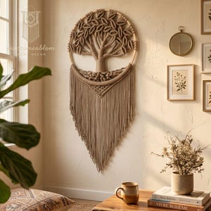Può includere: Un arazzo in macramè beige con un disegno di albero all'interno di un cerchio di legno, caratterizzato da un tronco annodato e dettagli a forma di foglia. La parte inferiore è composta da lunghe frange dritte che pendono a forma di V.