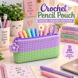 Può includere: Un astuccio rettangolare all'uncinetto con un design bicolore, caratterizzato da una sezione superiore viola chiaro e una sezione inferiore verde chiaro. L'astuccio presenta una cerniera viola con un piccolo fiore all'uncinetto attaccato.