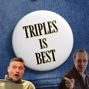 Könnte beinhalten: Ein weißer Button mit dem Text "TRIPLES IS BEST" in schwarzer und gelber Schrift. Der Button ist an einer blauen Jeansjacke befestigt. Zwei Männer sind im Bild, einer mit überraschtem Gesichtsausdruck und der andere zeigt.