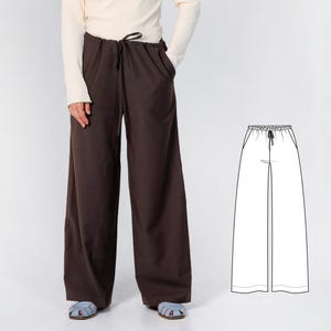 May include: Dark brown wide-leg trousers featuring an elasticized waistband with a matching drawstring tie. The pants have a relaxed, loose fit through the legs and include side pockets. A black and white line drawing of the pants is shown.