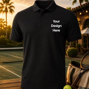May include: A black short-sleeved polo shirt with a collar and a three-button placket. The chest area features the white printed text "Your Design Here". The shirt is displayed as a standalone garment, showcasing its solid colour and texture.