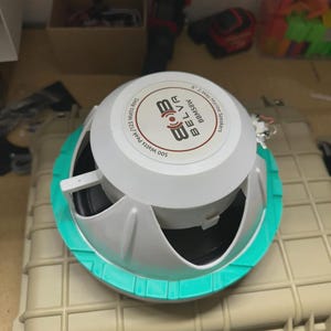 May include: A white and gray speaker with a teal-colored trim, labeled "BELVA BBMS8W 2-Way Marine Speakers." The speaker has a power rating of 500 Watts Peak / 125 Watts RMS. It is mounted on a beige, rectangular case.
