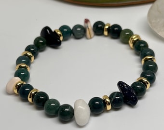 Puede incluir: Una pulsera elástica con cuentas verdes oscuras y doradas, intercaladas con piedras negras y blancas. La pulsera está diseñada para estirarse, adaptándose a diferentes tamaños de muñeca. Las cuentas redondas crean un accesorio elegante y sencillo.