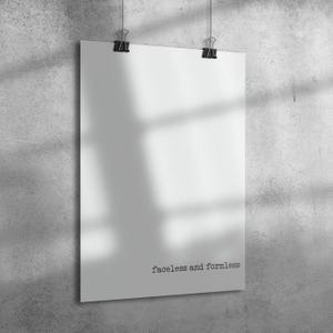 May include: A white poster with the text "faceless and formless" is suspended by two black binder clips. The poster hangs against a gray, textured wall, with shadows cast across its surface.
