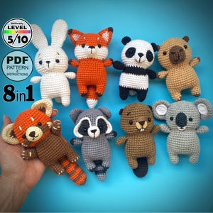Puede incluir: Una colección de ocho peluches de animales tejidos a ganchillo, incluyendo un conejo blanco, un zorro naranja, un panda, un oso, un panda rojo, un mapache, un castor y un koala. Los peluches hechos a mano tienen detalles y se muestran sobre un fondo azul. La imagen incluye texto que indica un patrón PDF.