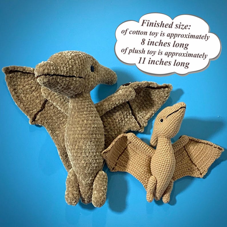 May include: Two crochet pterodactyl toys in shades of brown. The larger plush toy is approximately 11 inches long, while the cotton toy is about 8 inches long. The toys have wings and are set against a blue background. Text on the image indicates the finished sizes.