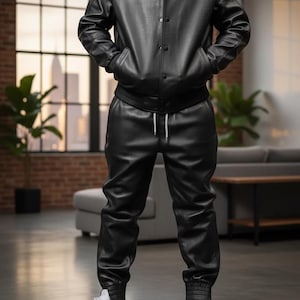 Pode incluir: Casaco de couro preto com bot&otilde;es, combinado com cal&ccedil;as de couro pretas a condizer. O conjunto inclui uma camiseta branca e t&ecirc;nis brancos. O casaco tem gola e bolsos. As cal&ccedil;as t&ecirc;m cintura com cord&atilde;o e punhos canelados. Uma vers&atilde;o moderna de um visual cl&aacute;ssico.