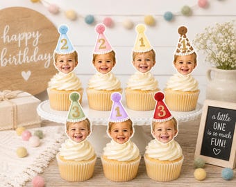 Könnte beinhalten: Sieben Cupcakes auf einer weißen Etagere, jeder mit einem personalisierten Fotoausschnitt eines Kindes verziert, das einen Miniatur-Partyhut trägt. Die Hüte sind in verschiedenen Farben wie Blau, Pink, Gelb, Braun, Grün, Lila und Rot gehalten.