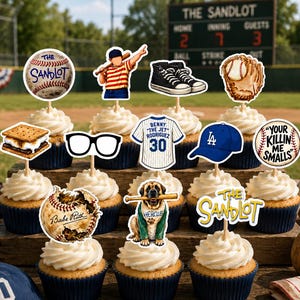 K&ouml;nnte beinhalten: Ein Set aus zw&ouml;lf Cupcakes mit Baseball-Motiv-Aufsteckern aus Papier, darunter ein Baseball mit dem Text The Sandlot, ein Spieler, schwarze Turnschuhe, ein Handschuh, ein S'more, eine Brille, ein Trikot, eine blaue Kappe und ein Hund.