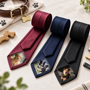 Op de afbeelding: Drie dassen in bordeauxrood, marineblauw en zwart, elk met een aangepaste hondenfoto op de onderste punt. Drie metalen dasspelden zijn inbegrepen, gegraveerd met de zinnen My Best Friend en Always With You, vergezeld van pootafdrukken.