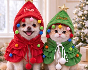 May include: A red pet cape with a hood, a gold star topper, and colorful pom-poms, embroidered with the name Daisy. Beside it, a green pet cape with a hood, a gold star topper, and colorful pom-poms, embroidered with the name Cooper.