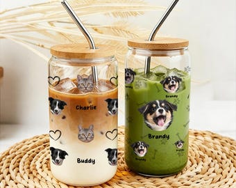 May include: Two glass tumblers with bamboo lids and stainless steel straws. One tumbler contains a layered coffee drink with cat and dog graphics and the name "Charlie" and "Buddy". The other contains a green drink with dog graphics and the name "Brandy".