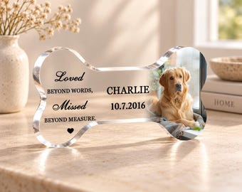 May include: A clear, bone-shaped acrylic memorial plaque featuring a photograph of a golden retriever. The text reads: Loved BEYOND WORDS, Missed BEYOND MEASURE. CHARLIE 10.7.2016, with a small black heart icon below the text.