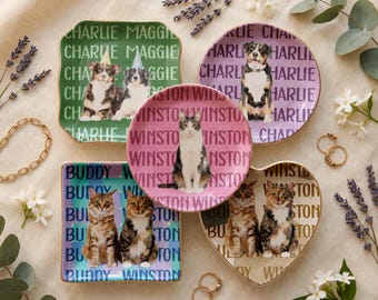 May include: Five ceramic dishes in square, round, and heart shapes featuring custom pet portraits and repeated names. The green square dish shows two dogs, the purple round dish a dog, the pink round dish a cat, and the others show cats.
