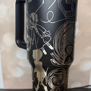 May include: A white ceramic mug with a black handle and the text "But First, Coffee" in a bold, black font. The mug is sitting on a wooden surface. The mug is approximately 4 inches tall.