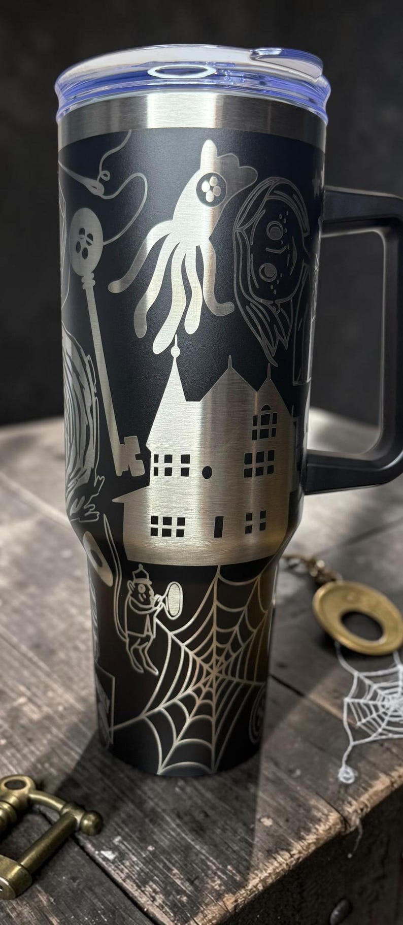 May include: A white ceramic mug with a black handle and the text "But First, Coffee" in a bold, black font. The mug is set against a blurred background, suggesting a cozy setting.