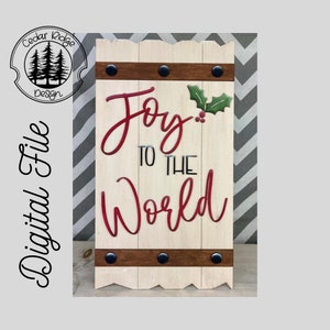 May include: A white wooden sign with a red and green holly design and the text "Joy to the World". The sign has a brown wooden strip with black metal accents at the top and bottom.