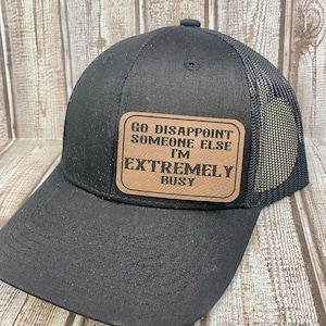 May include: Black trucker hat with a brown leather patch that reads "Go Disappoint Someone Else I'm Extremely Busy".