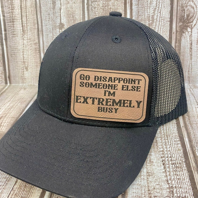 May include: Black trucker hat with a brown leather patch that reads "Go Disappoint Someone Else I'm Extremely Busy".