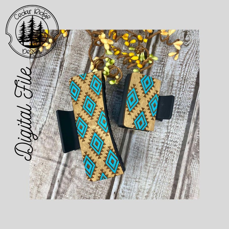 May include: Two wooden hair clips with a geometric pattern in shades of brown and turquoise. The clips are on a wooden surface.