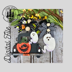 Puede incluir: Decoración de Halloween de madera con un camión negro, una calabaza naranja y dos adornos de fantasmas. El camión tiene la palabra "Boo" en la parte trasera. Los fantasmas son blancos con sombras moradas. Lazos decorativos completan el diseño.
