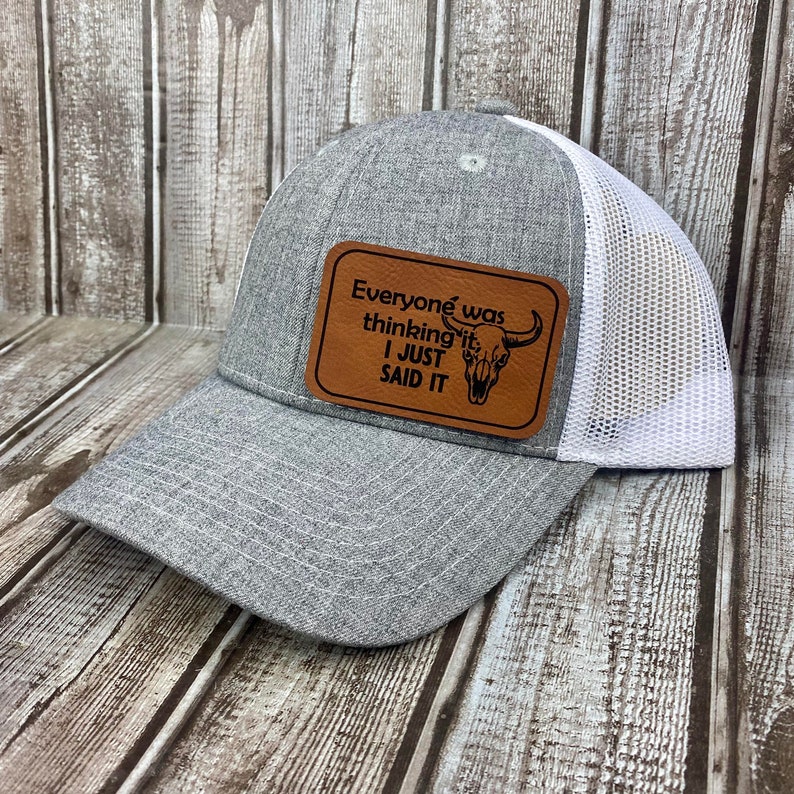 May include: Gray and white trucker hat with a brown leather patch that says "Everyone was thinking it I just said it" with a skull and horns graphic.