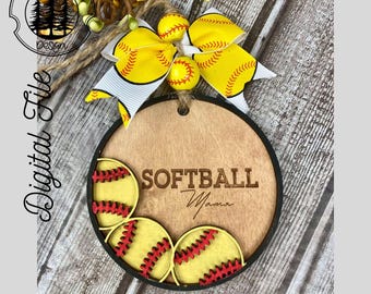 May include: A wooden round sign with the text "SOFTBALL Mama" and a black border. The sign is decorated with four yellow and red softball cutouts.