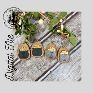 May include: Three pairs of wooden earrings with a pot of gold design. Each earring features a gold pot with gold coins and the text "POT O GOLD". The earrings are available in three different wood finishes: natural, black, and silver.