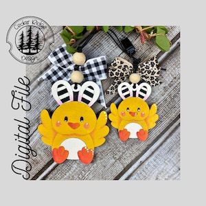 May include: Two wooden Easter chick ornaments with bunny ears. The chicks are yellow with orange feet and beaks. One has a black and white checkered bow, the other a leopard print bow. The text "Digital File" is on the left side.