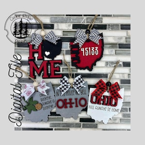 May include: Five wooden Ohio-shaped decorations with different designs. The decorations are painted in red, black, white, and grey. The designs include the words "Home", "Ohio", "Once a Buckeye, Always a Buckeye", "In this house we yell Ohio", and "Ohio will always be home". The decorations are adorned with black and white checked bows.