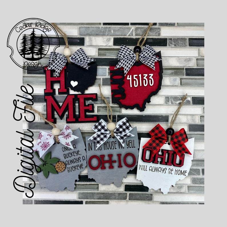 May include: Five wooden Ohio-shaped decorations with different designs. The decorations are painted in red, black, white, and grey. The designs include the words "Home", "Ohio", "Once a Buckeye, Always a Buckeye", "In this house we yell Ohio", and "Ohio will always be home". The decorations are adorned with black and white checked bows.