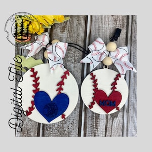 May include: Two wooden baseball-themed ornaments with red and white ribbon bows. One ornament has a blue heart with a Native American design, and the other has a red heart with the word "MOM" on it.