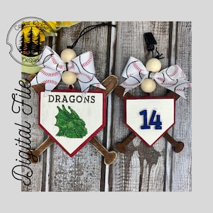 Può includere: Due ornamenti a tema baseball. Uno presenta la parola "DRAGONS" e un'illustrazione di drago verde, l'altro il numero "14". Entrambi hanno una combinazione di colori bianco, rosso e marrone, con accenti di mazza da baseball e fiocchi di nastro da baseball.