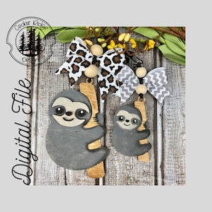May include: Two wooden sloth ornaments, one large and one small, hanging from a wooden branch. The sloths are grey with light brown accents. Two decorative bows with wooden beads are at the top. The text "Digital File" is on the left.