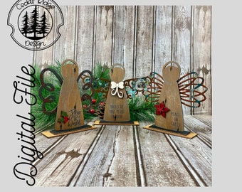 Op de afbeelding: Drie houten engelbeeldjes met vleugels, elk met een andere boodschap: "Joy to the World", "Angels We Have Heard On High" en "Peace On Earth".