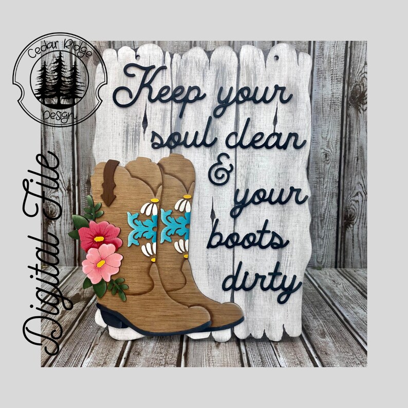 May include: Wooden sign with a whitewashed wood background and black lettering that reads "Keep your soul clean & your boots dirty". Two brown cowboy boots with turquoise and white floral designs are attached to the sign.