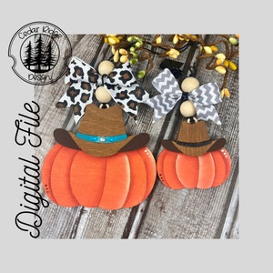 Può includere: Due decorazioni di zucca in legno con cappelli da cowboy e fiocchi. La zucca più grande è arancione con un cappello da cowboy marrone e una fascia turchese. Ha un fiocco con stampa leopardata. La zucca più piccola è arancione con un cappello da cowboy marrone e un fiocco a chevron grigio e bianco.
