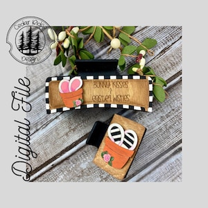 Könnte beinhalten: Zwei hölzerne Haarklammern zum Thema Ostern. Die obere Klammer hat einen schwarz-weißen karierten Hintergrund mit dem Text "Bunny Kisses & Easter Wishes". Die untere Klammer hat einen schwarz-weiß gestreiften Hasen in einem Topf mit rosa Blumen.