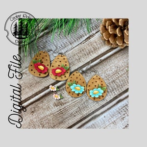 May include: A set of four wooden earrings with floral designs. Two earrings feature red flowers with yellow centres and green leaves, while the other two feature blue flowers with yellow centres and green leaves. The earrings are all oval-shaped and have a brown wood finish with white polka dots.