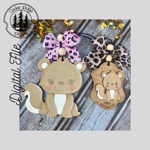 May include: Two wooden squirrel ornaments with pink cheeks and bows. One is a full squirrel, the other is on a wooden plaque with the text "easily distracted". The ornaments are tan, white, and pink.